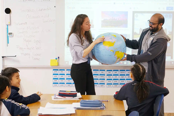 Teachers showing globe to children